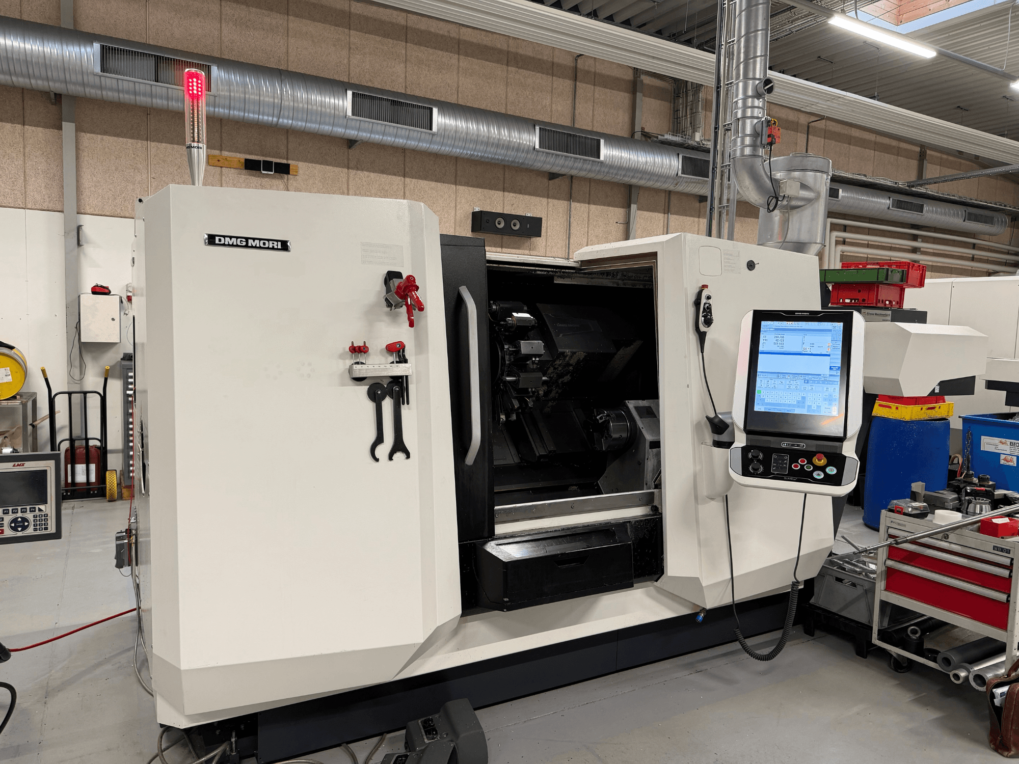 Tour horizontal DMG MORI CLX 450 V6, vue de face montrant le panneau de commande, l'arrêt d'urgence et le voyant de sécurité.