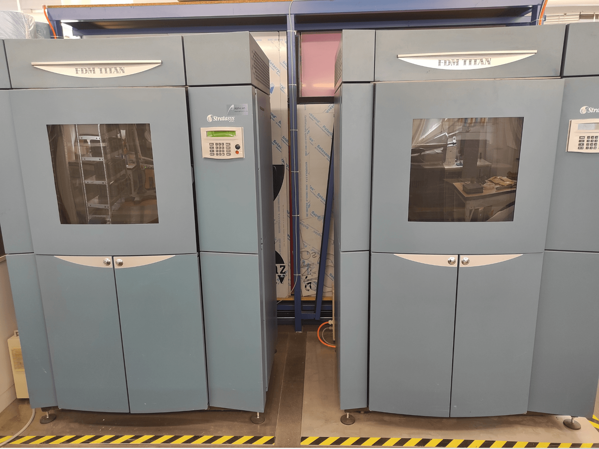 Vue de face de l'imprimante 3D à plastique Stratasys FDM TitanTI T0031 ; elle est équipée d'un écran d'affichage et d'une fenêtre transparente.