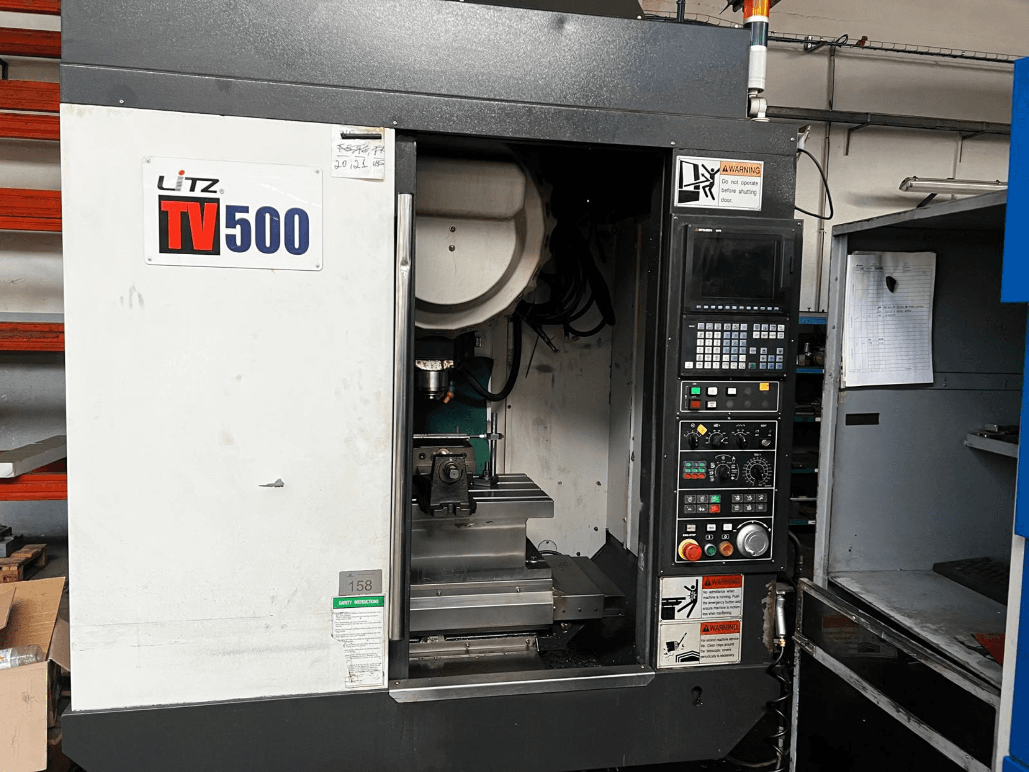 Vue de face du centre d'usinage vertical Litz TV500, montrant le panneau de commande, la broche et la zone d'usinage à l'intérieur de la machine.