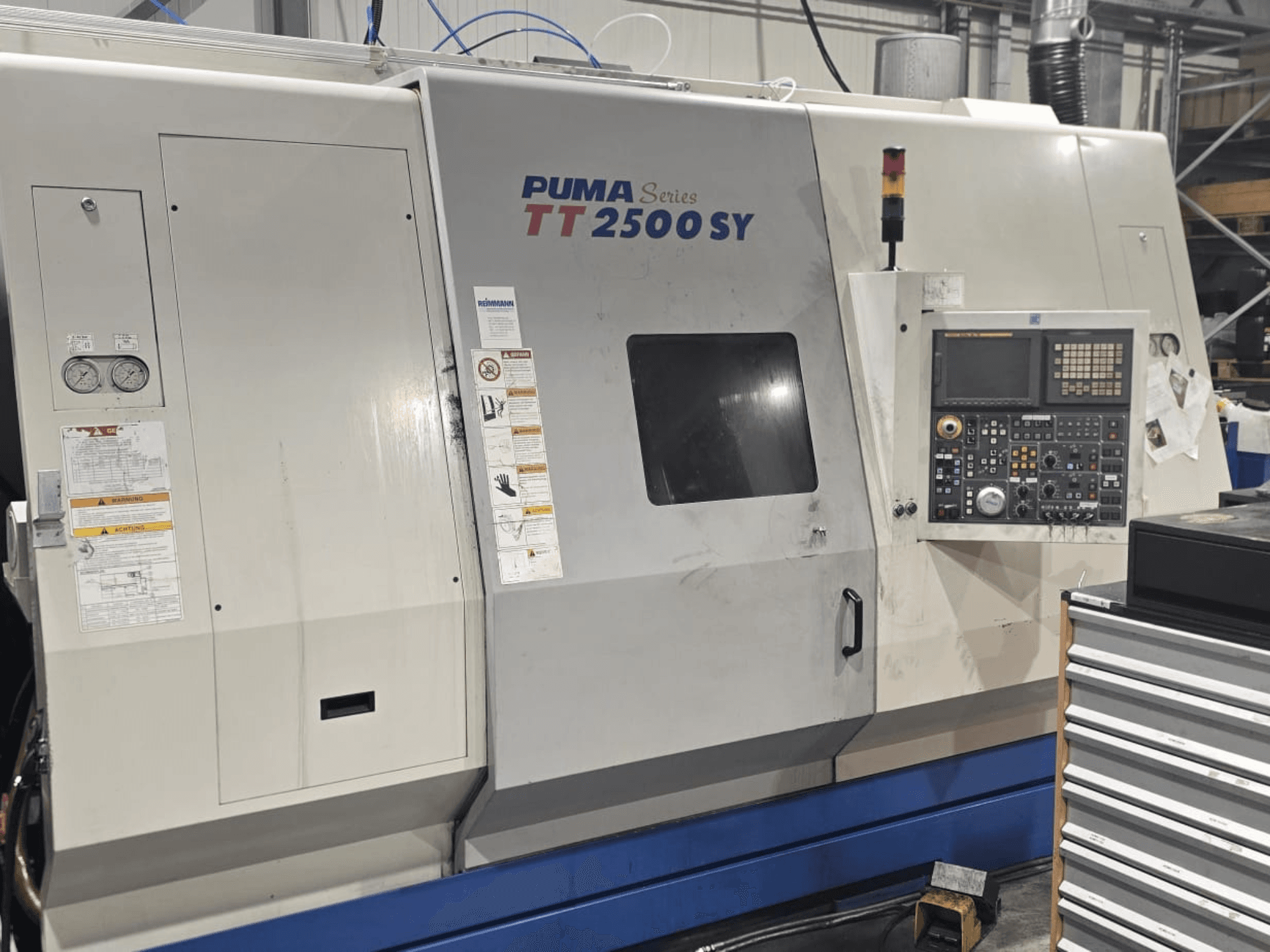 Tour CNC PUMA série TT 2500 SY, vue de face ; panneau de commande avec cadrans et boutons, jauges et étiquettes d'opération visibles.