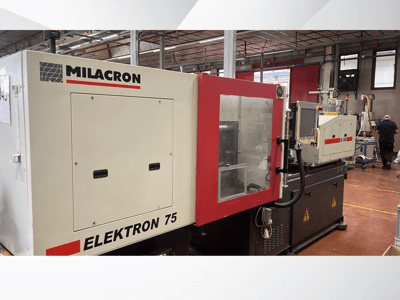 Machine de moulage par injection Milacron Elektron 75 dans un atelier, vue latérale montrant le panneau de commande et les pièces mécaniques.