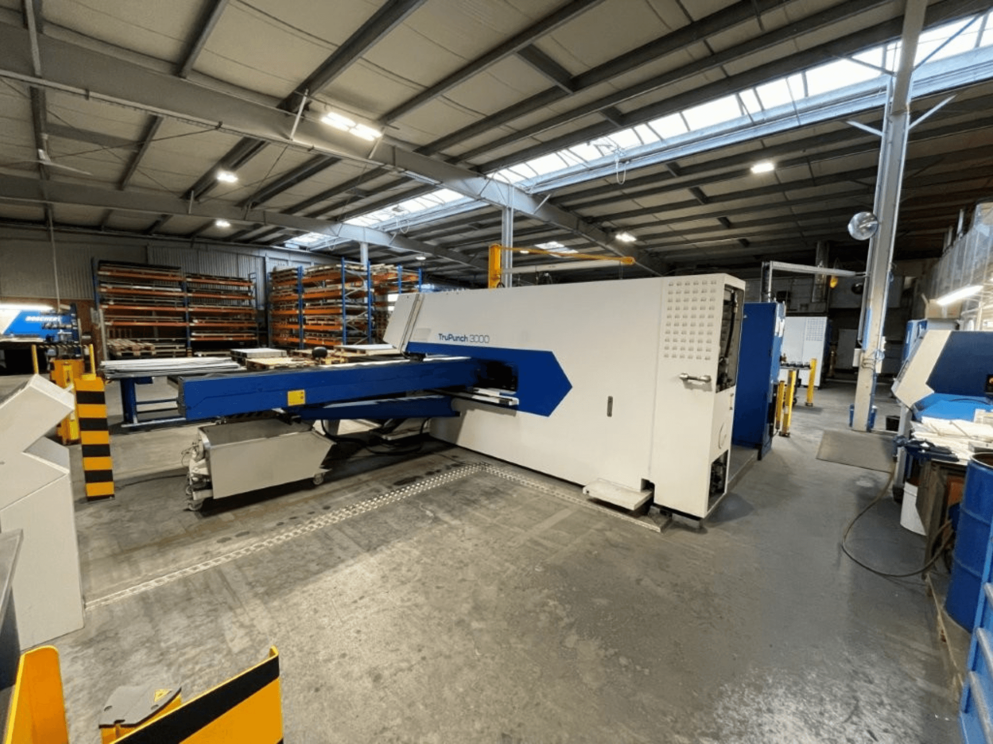 La presse à poinçonner CNC TRUMPF TruPunch 3000 dans son environnement d'usine : cette vue de face met en valeur son design bleu et blanc ainsi que ses composants opérationnels.