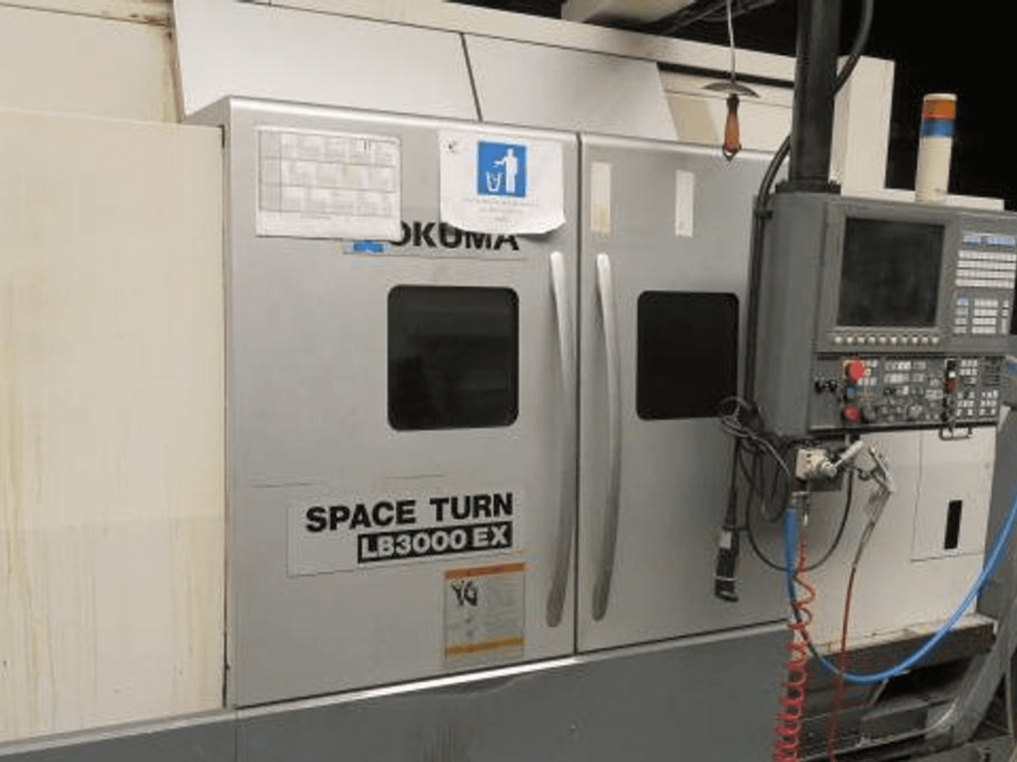 Tour CNC Okuma Space Turn LB3000 EX, vue latérale, avec panneau de commande, deux portes et câblage visible.