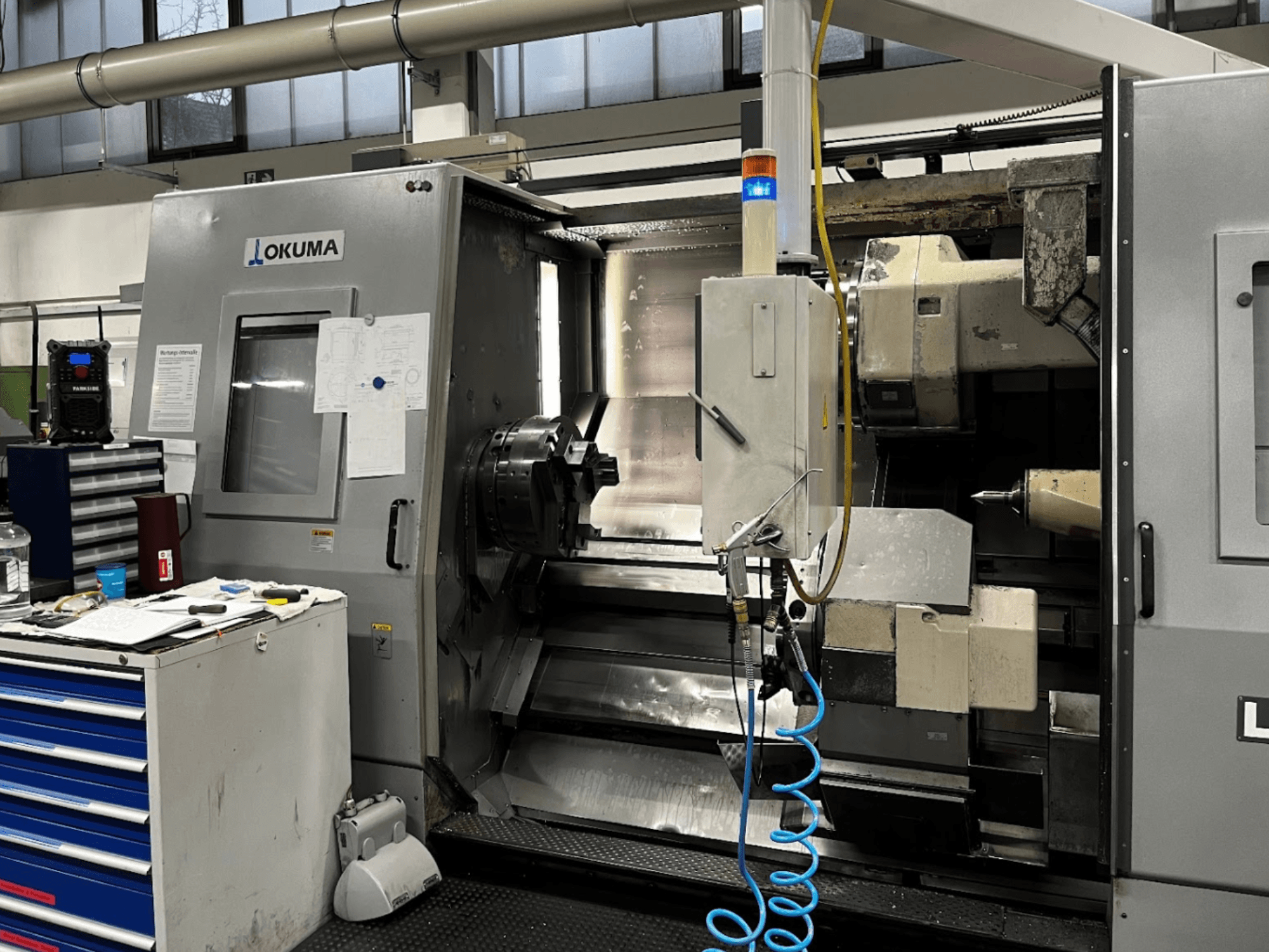 Tour horizontal Okuma LU35-M, vue de face. Panneau de commande, outils et grand mandrin pour les opérations d'usinage.