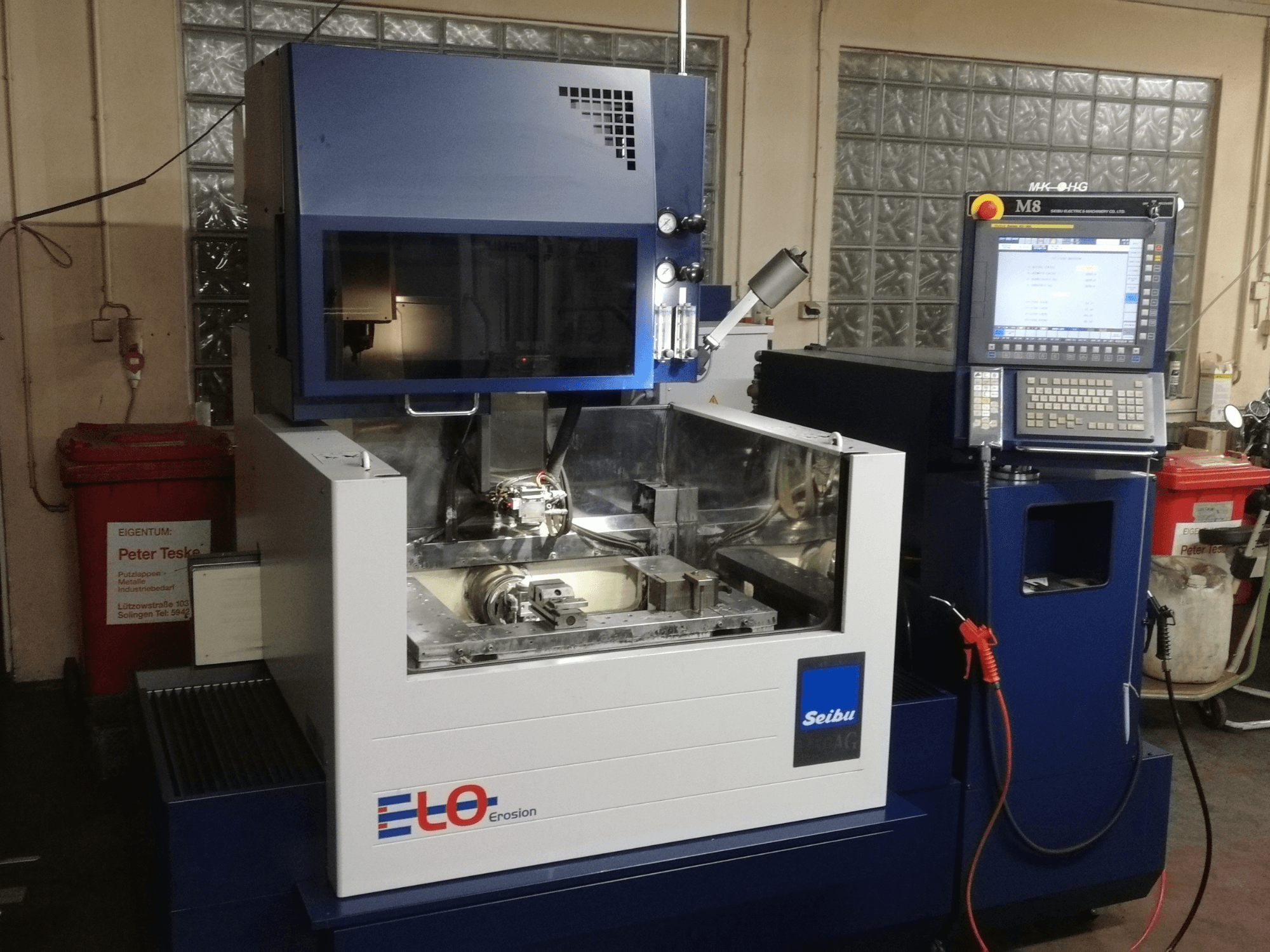 Machine d'érosion ELO Seibu vue de face, comportant un panneau de commande et une zone de travail visible avec des composants métalliques.