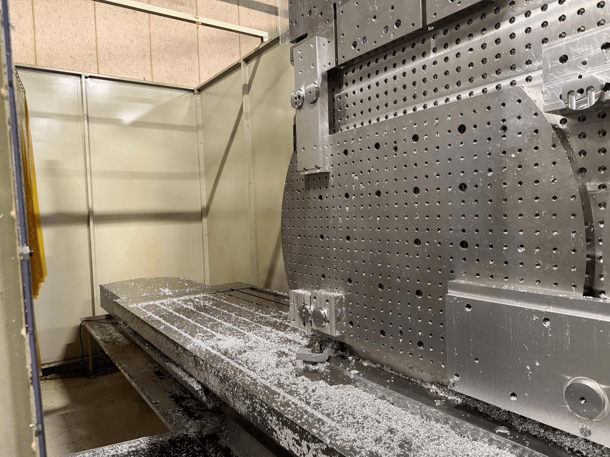 Vue frontale en gros plan du centre d'usinage universel KIHEUNG KNC-U1000, montrant une table de travail métallique avec des copeaux d'aluminium.