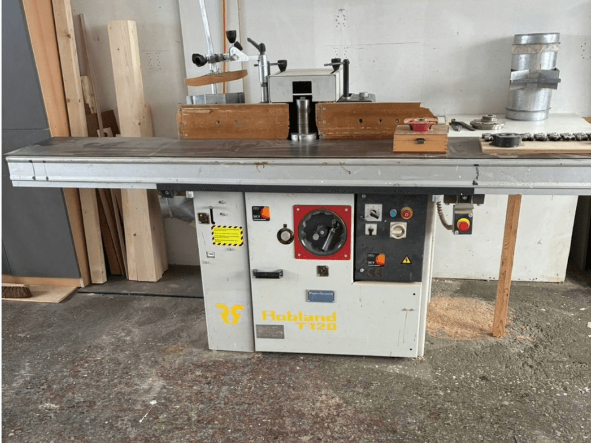 La raboteuse de table Hobbland T120, vue de face, présente une surface argentée, un panneau de commande avec des boutons et des étiquettes de sécurité.